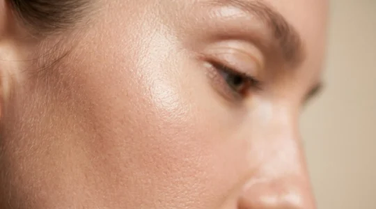 Primer plano de piel facial con textura uniforme y poros refinados mostrando luminosidad natural