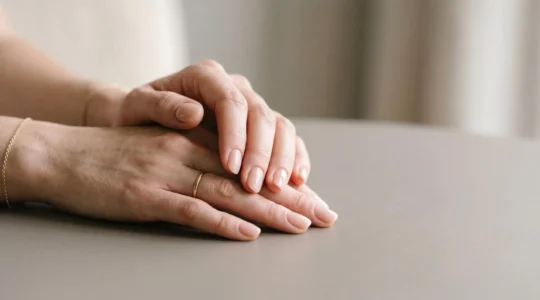 Manos femeninas mostrando uñas reconstruidas con acabado natural y manicura profesional